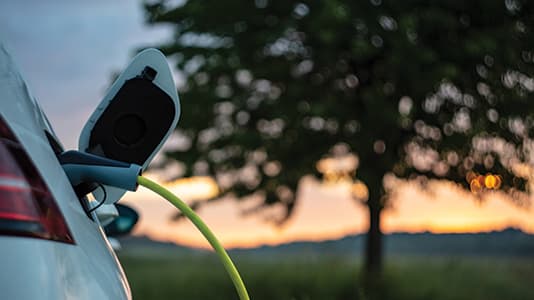 A photo of an electric vehicle charging as the sunsets.