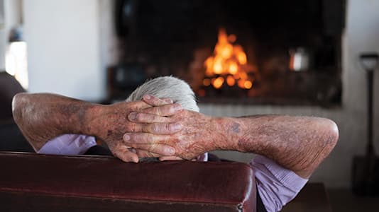 A grandfather heating up by the fire.