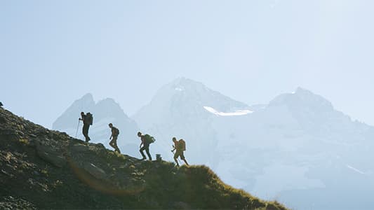 A landscape photo of four people walking up a mountain.