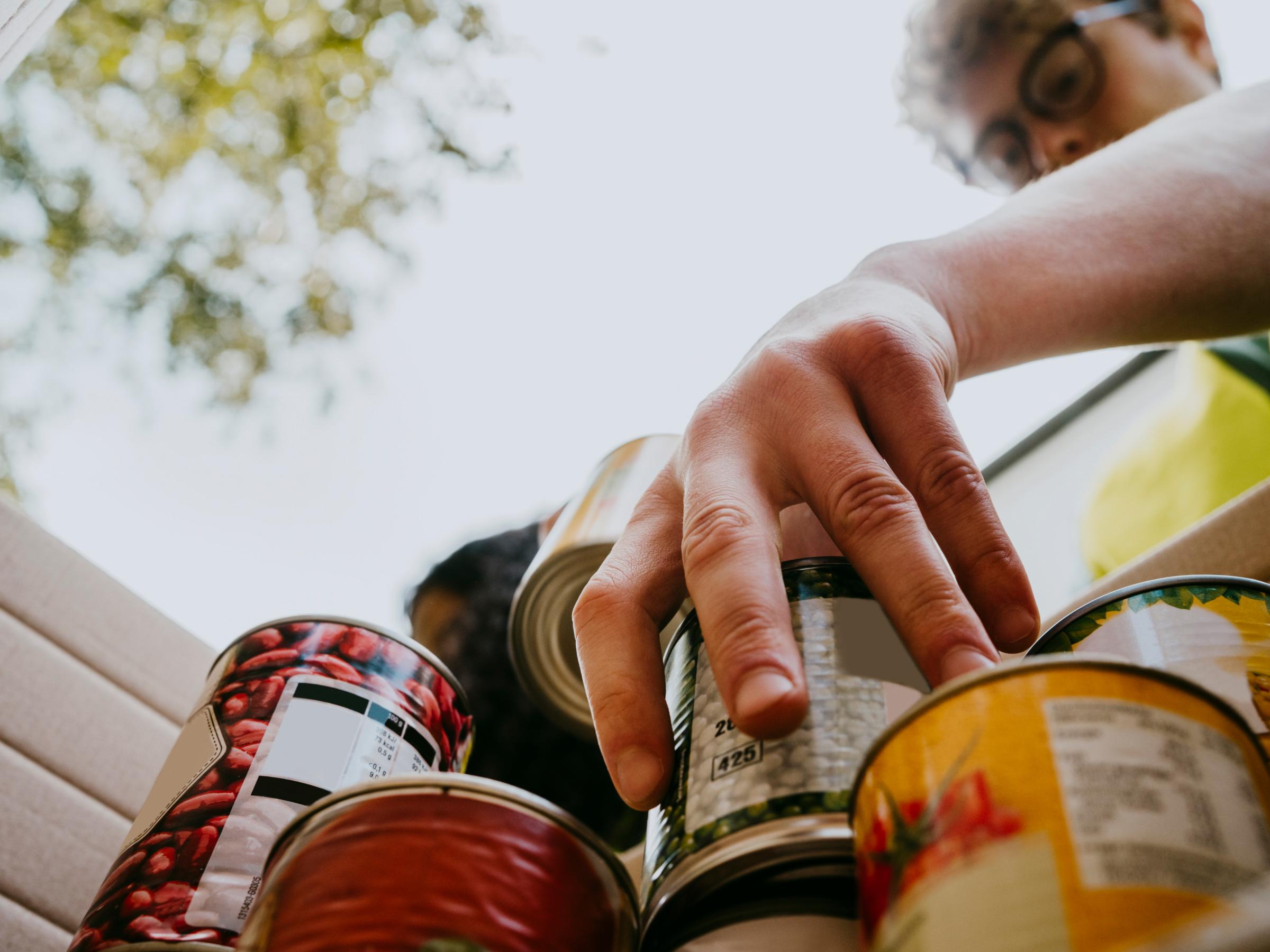 A low angle shot of a man collecting cans of food for a community group.