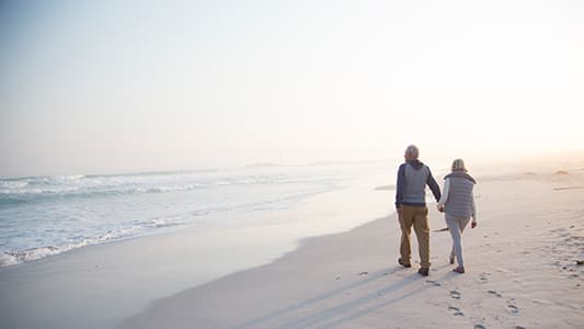 A couple walking down the beach as the tide turns.