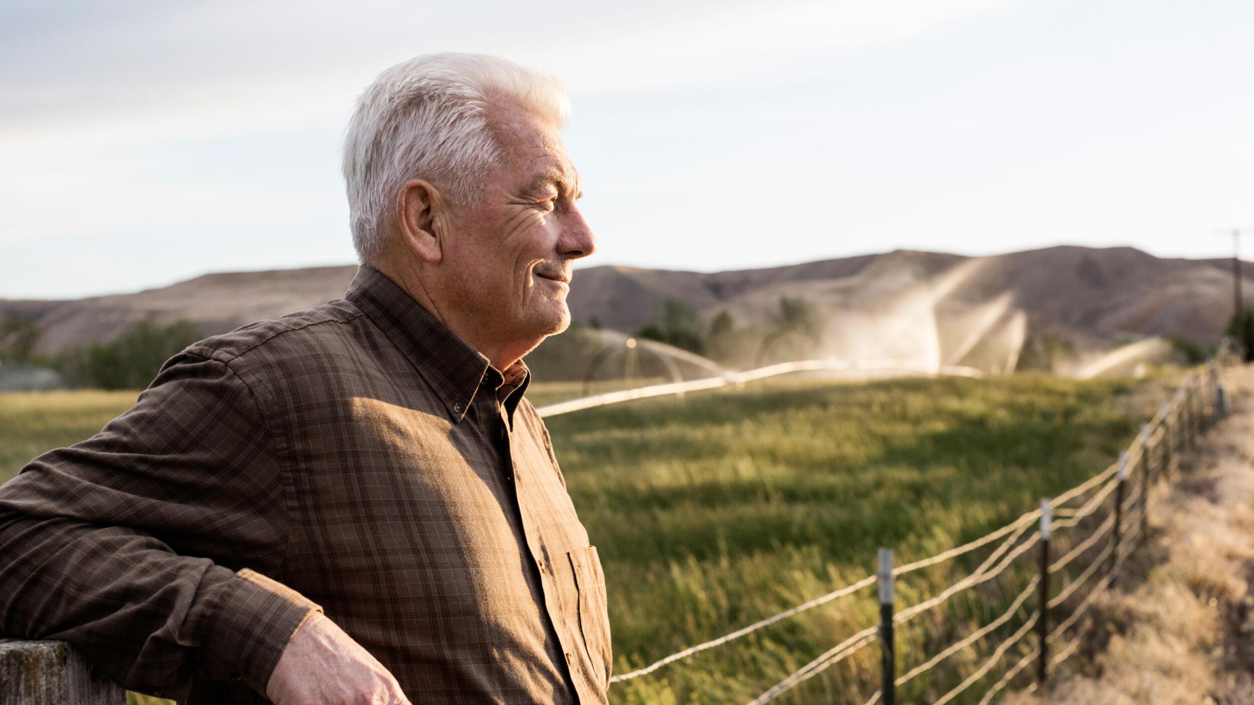 A farmer smiling as he watches his growing crops.