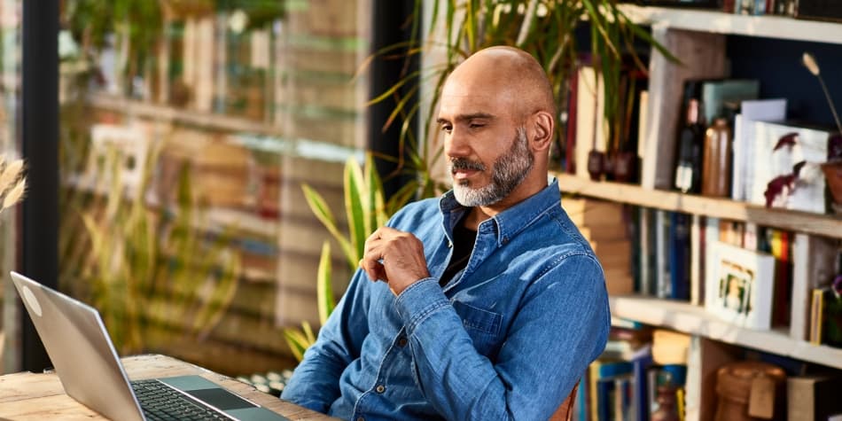 A bald man is educating himself on the nations s deb and if it applies to them by reading a book.